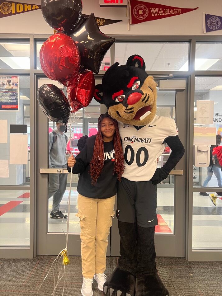 Student posing with the Bearcat mascot and balloons
