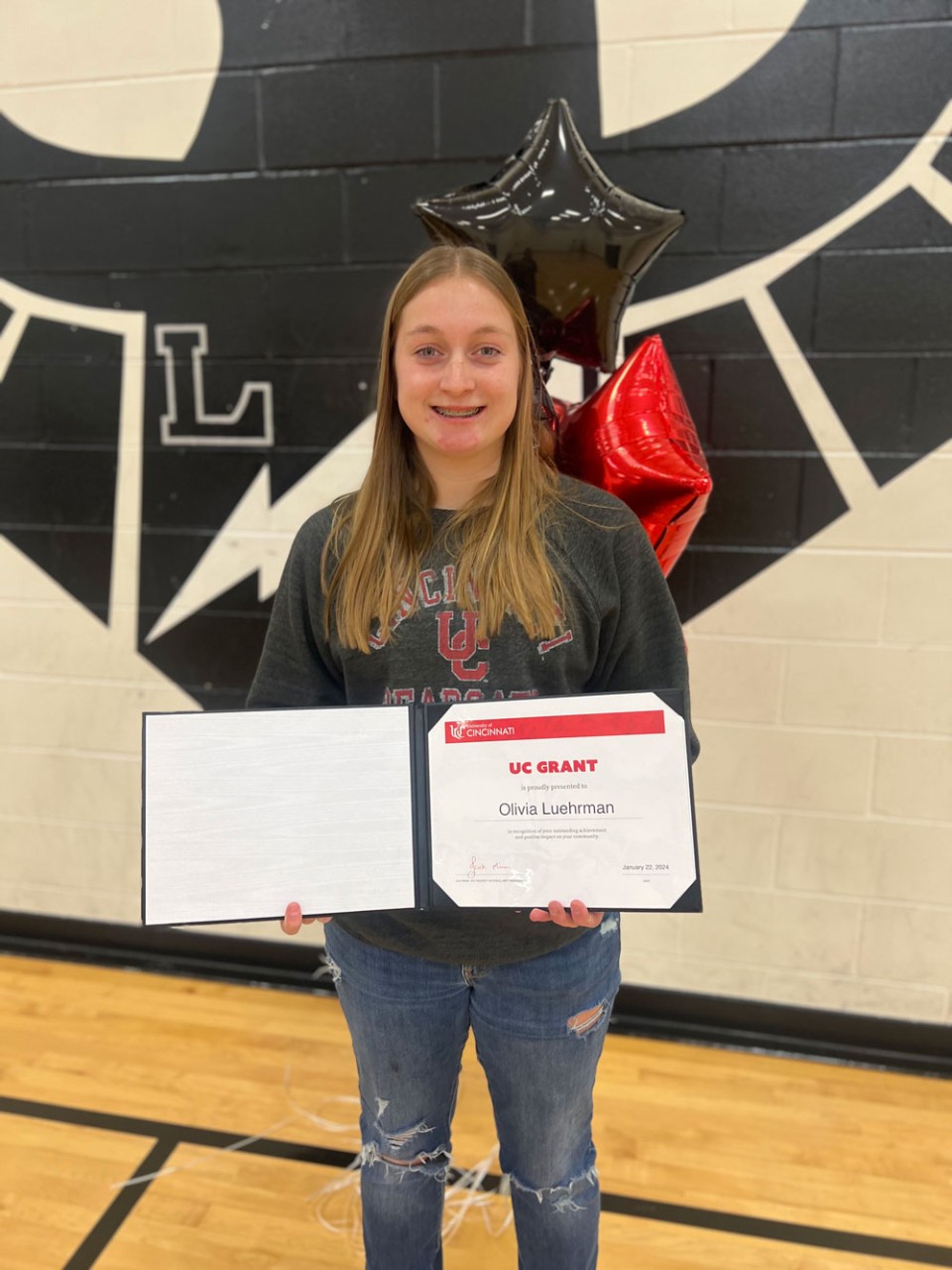 Student smiling and holding a grant certificate