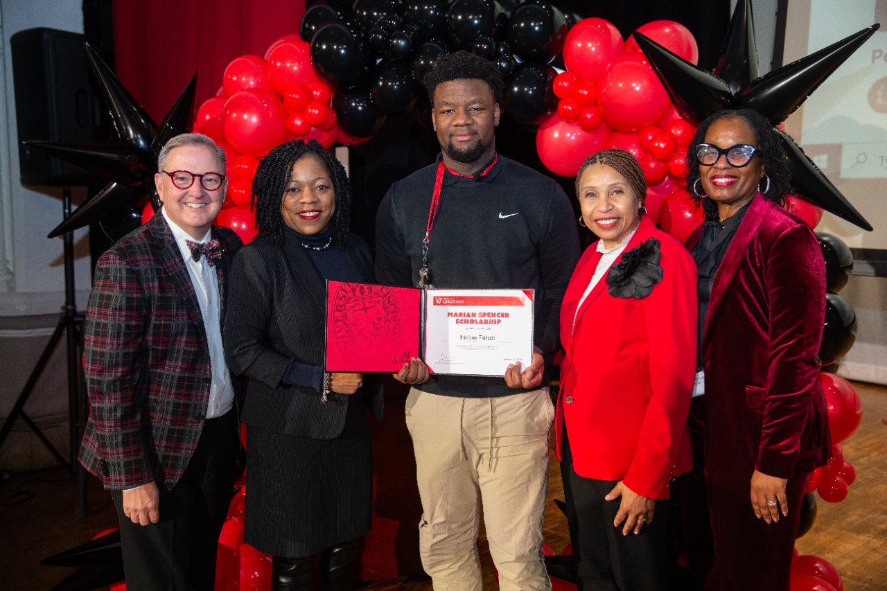 UC surprises Marian Spencer Scholar Fiston Feruzi at Hughes High School.