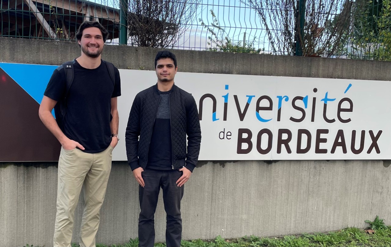 Will Mnich (left) and another student pose in front of the sign at the University of Bordeaux in France
