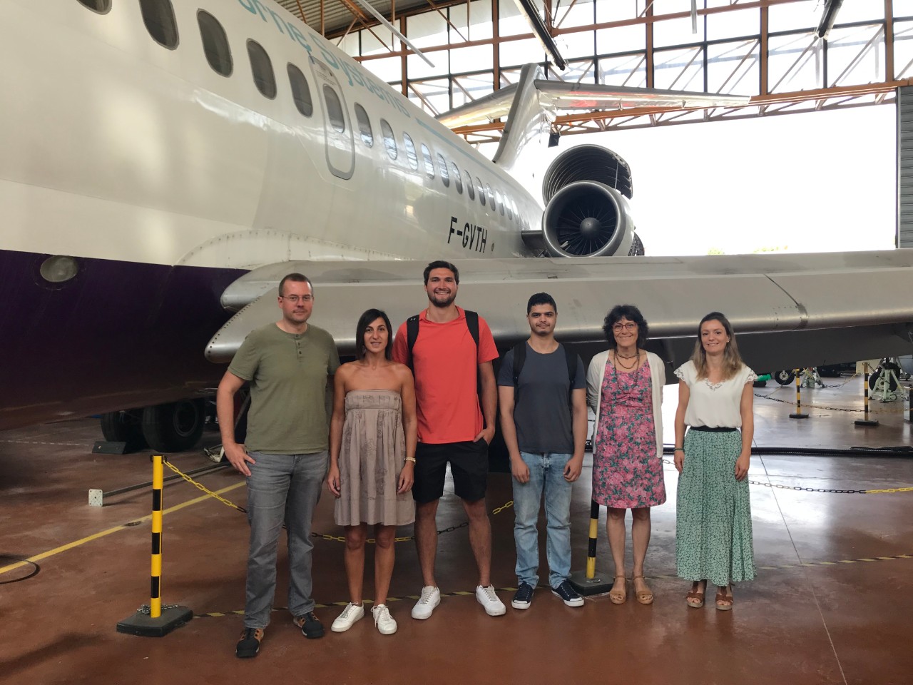 Mnich and others pose in front of airplane at hangar