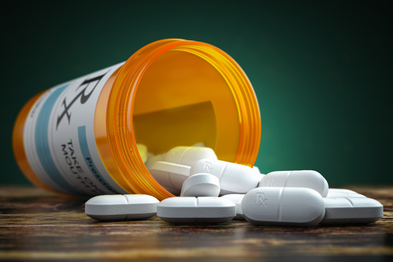Pills spilling out from a yellow pill bottle.