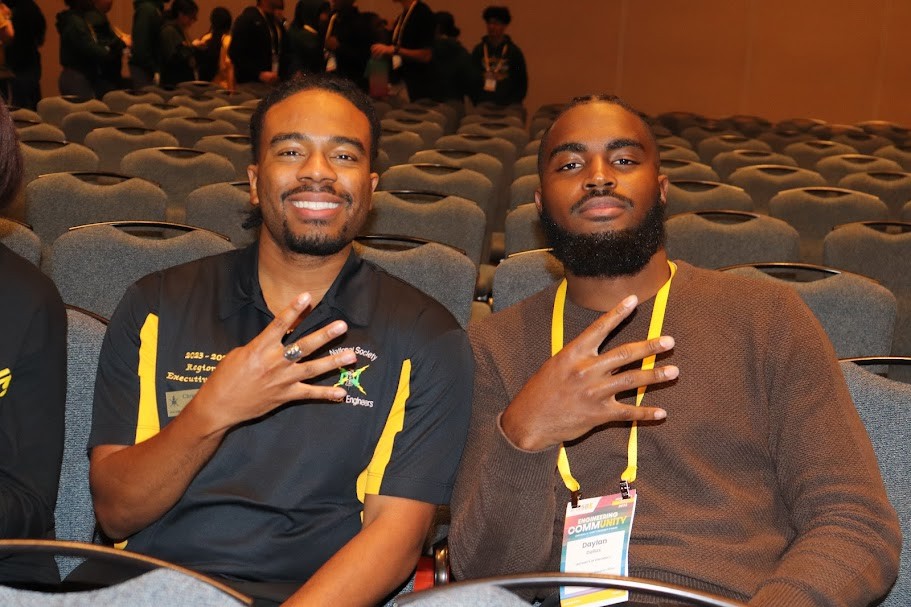 Chris Boles (left) and another NSBE member hold up 4's with their fingers. 