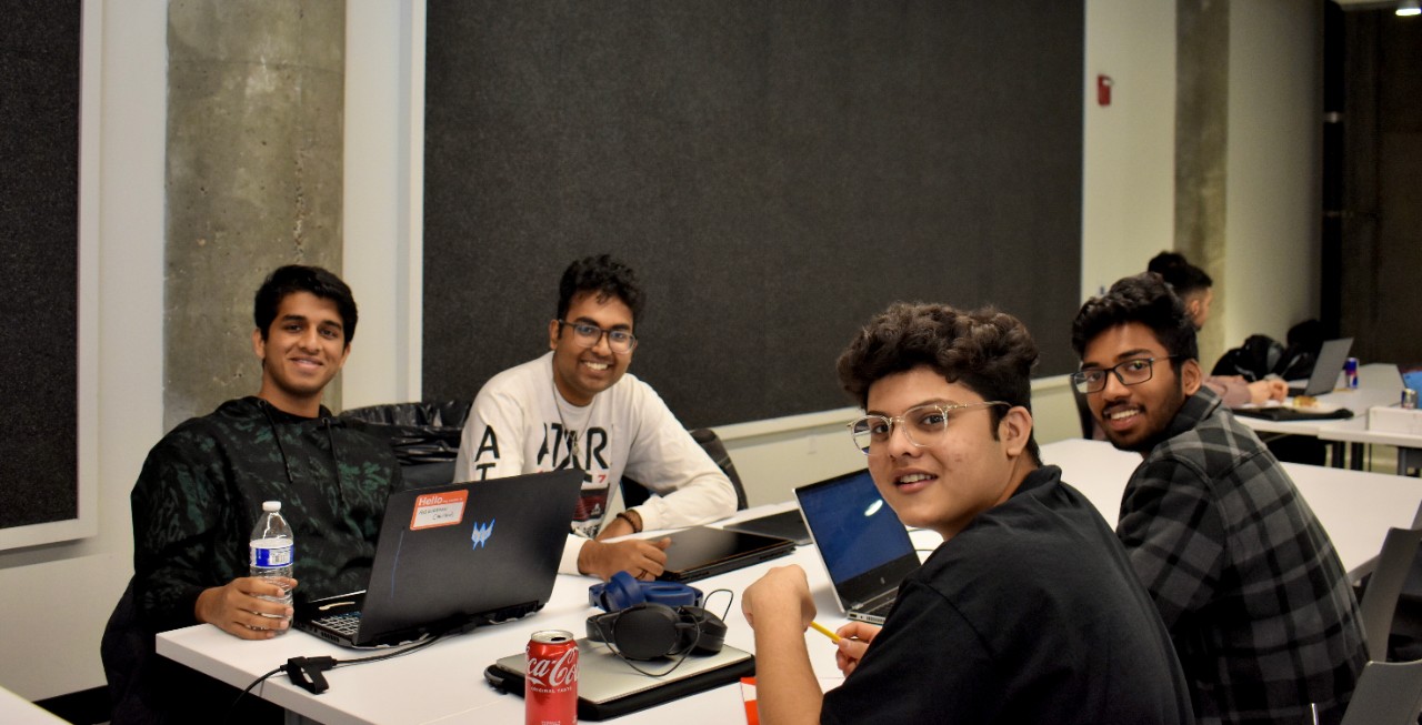 Students engage with team members during hackathon event.
