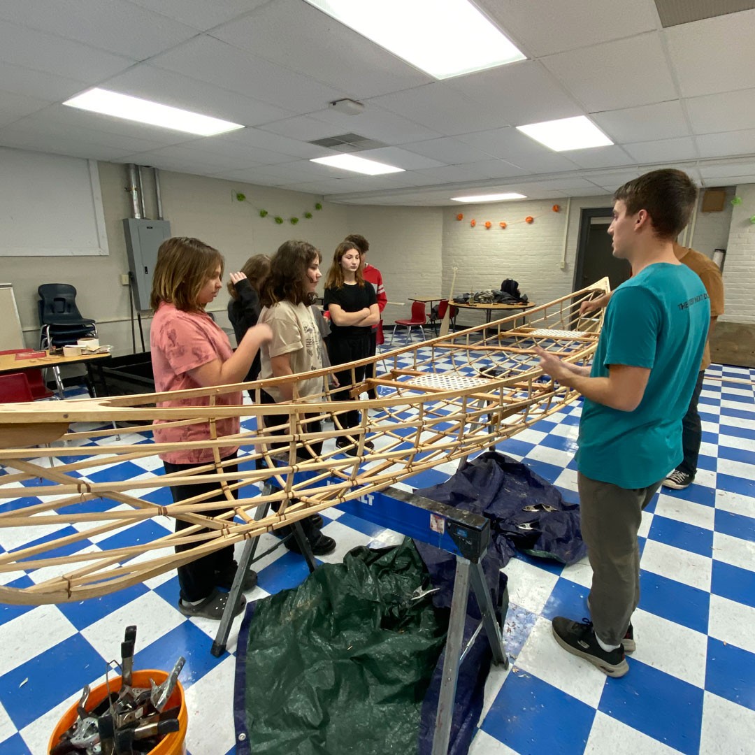 four students around a canoe frame