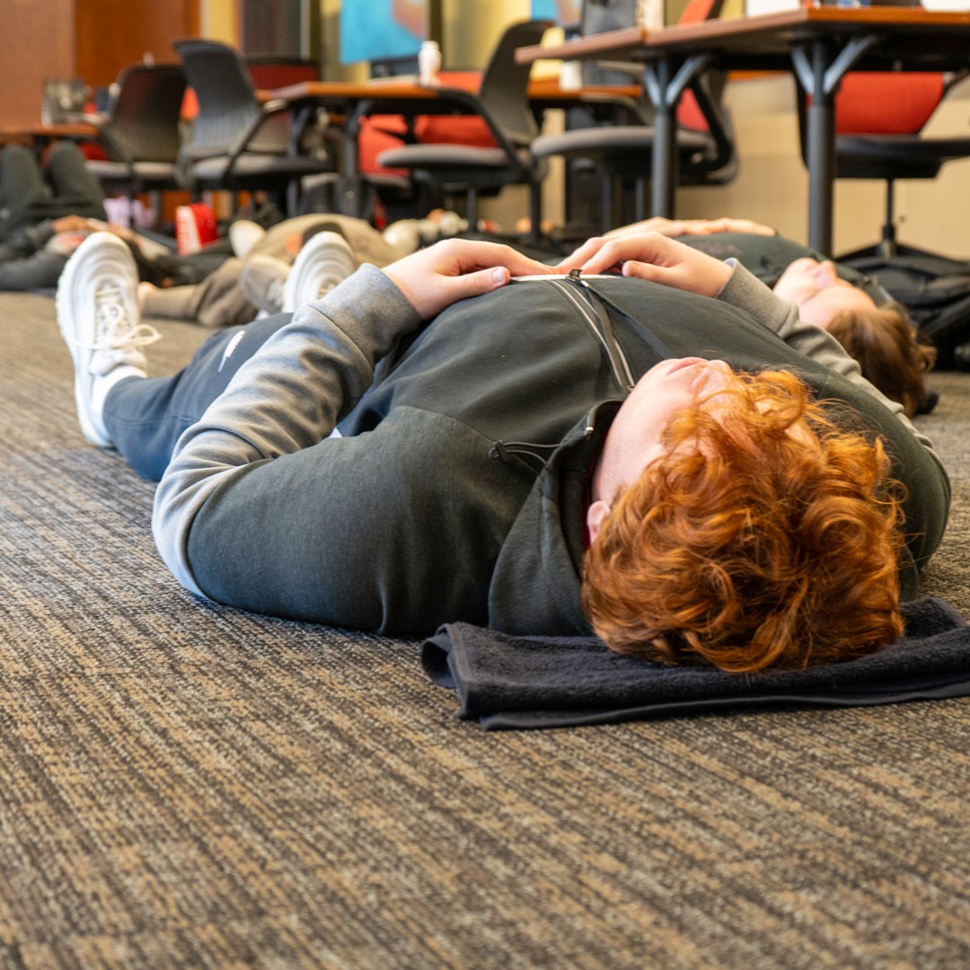 student lays on the ground with hands crossed on abdomen