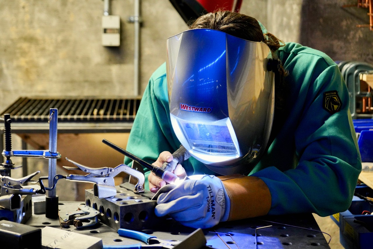 UC grad student Jacob Hoffmann wears a welding shield while working with welding tools in UC's Makerspace