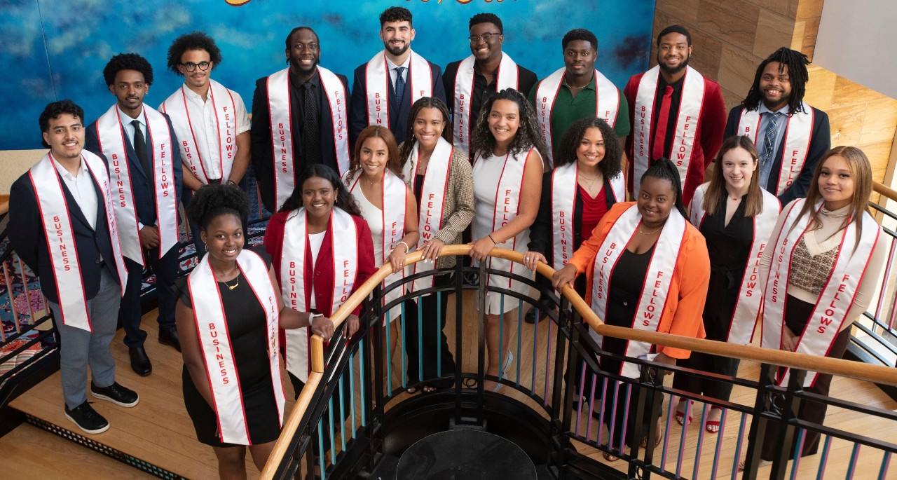 Graduating Business Fellows stand together on a staircase.