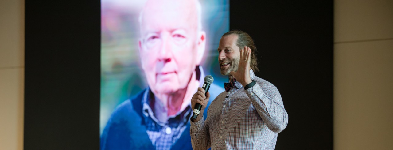 Dr. Robert Neel in front of Hugh Hoffman photo.