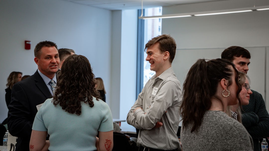 man in suit speaks with students