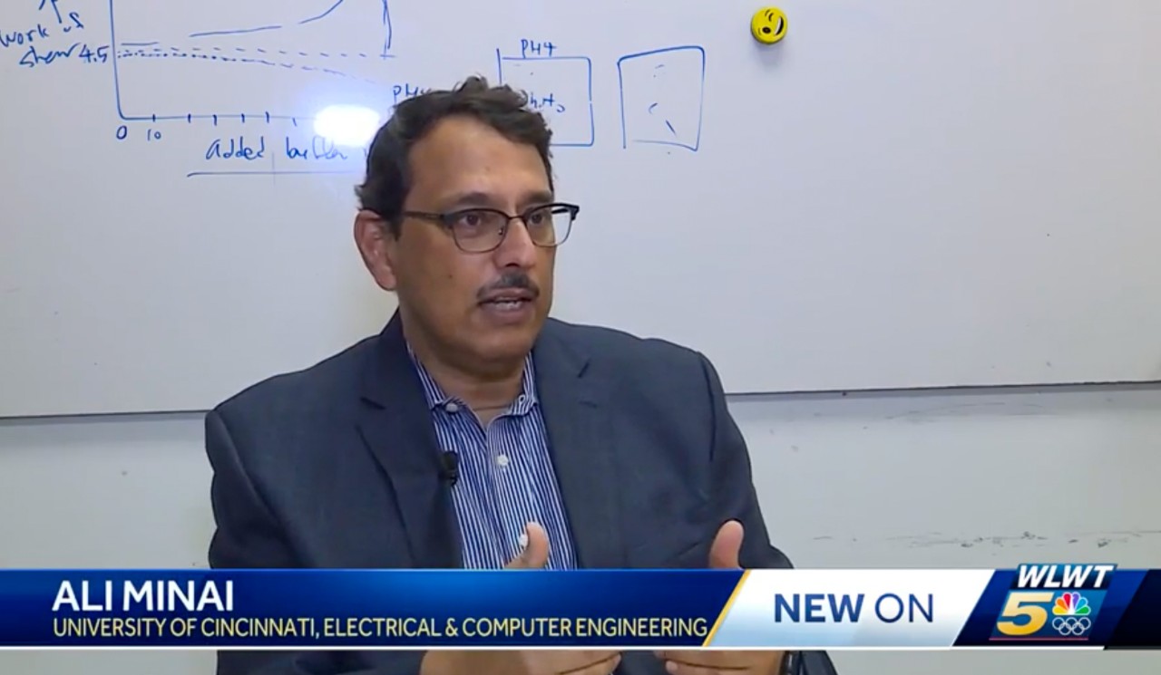 Ali Minai talks in front of a white board on WLWT.