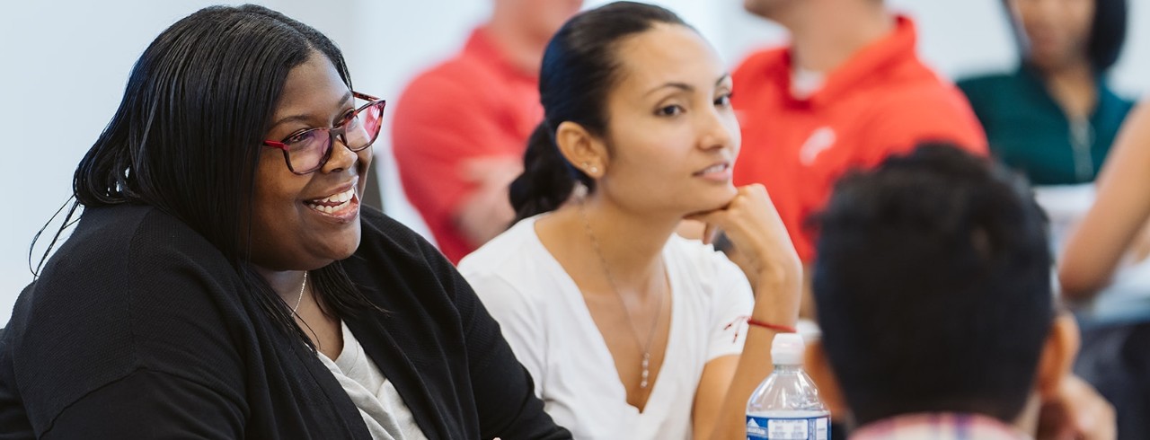 Two female MBA students engage in conversation with other students in a Lindner Hall classroom on the first day of school