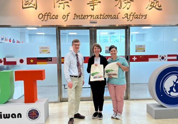 Faculty holding signs in front of doors at Office of International Affairs at Ming Chi University of Technology