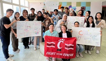 Faculty and  students hold a UC banner and signs at Ming Chi University of Technology