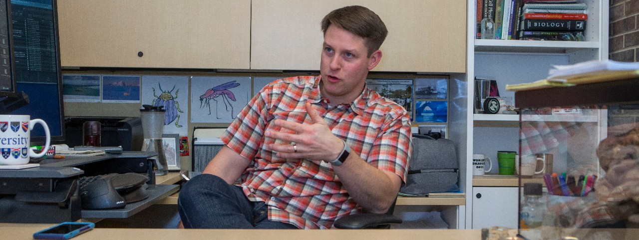Joshua Benoit gestures while talking in hs office.