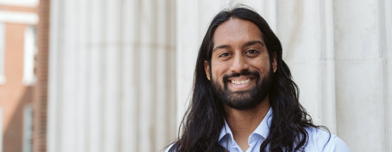 Portrait of UC student Jonathan Raj with campus building columns in background.