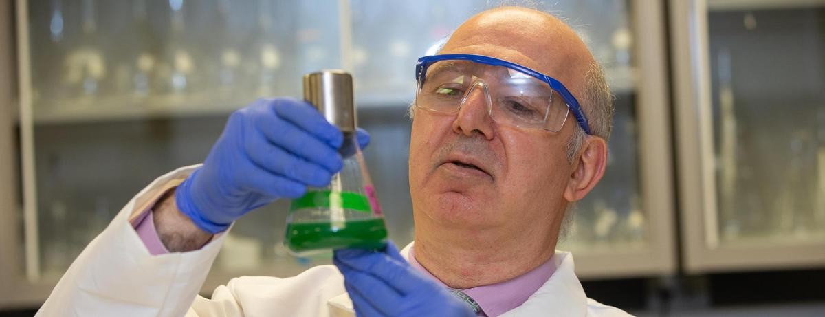 Dionysios Dionysiou looks at a flask with green liquid in his lab.