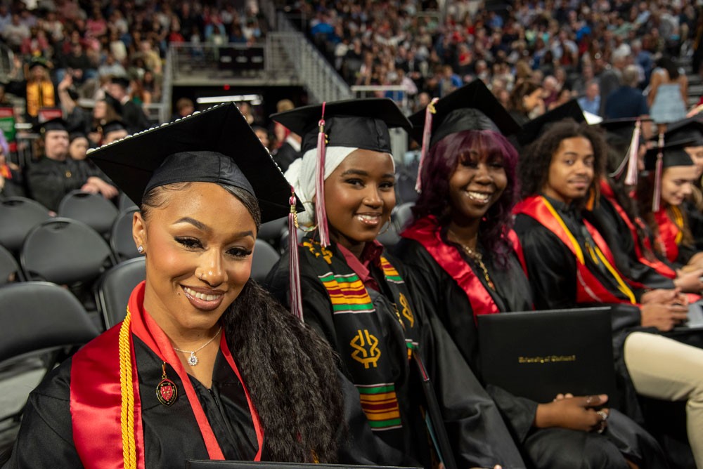 Row of students in caps and gowns sitting at commencement ceremony