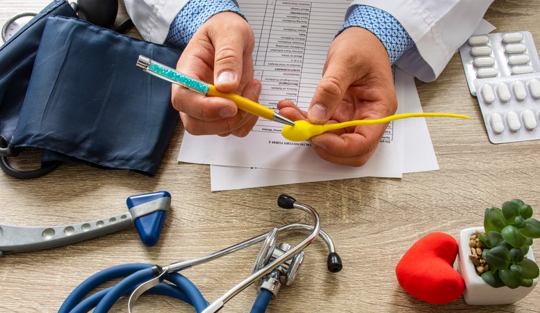 A doctor holds a yellow model of sperm over a desk