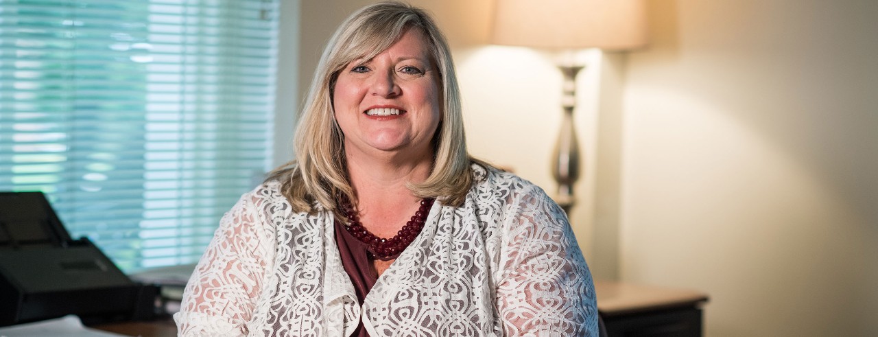 Lisa Huffman smiles while sitting at an office desk