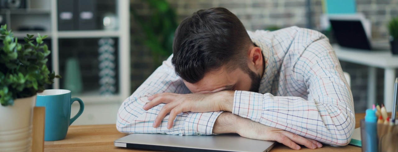 Portrait of man laying on his closed laptop.