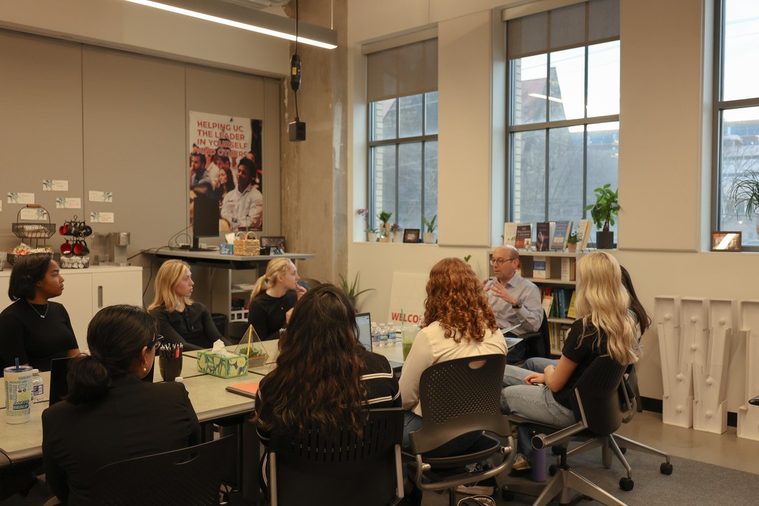 eight young women seated at a table and engaged with former hospital CEO Michael Fisher