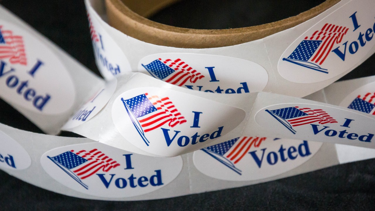 A closeup of a roll of I voted stickers featuring the American flag.