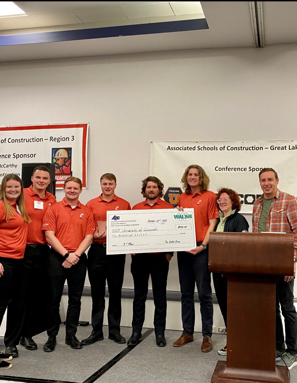 several UC students pose with a giant check after being awarded. 