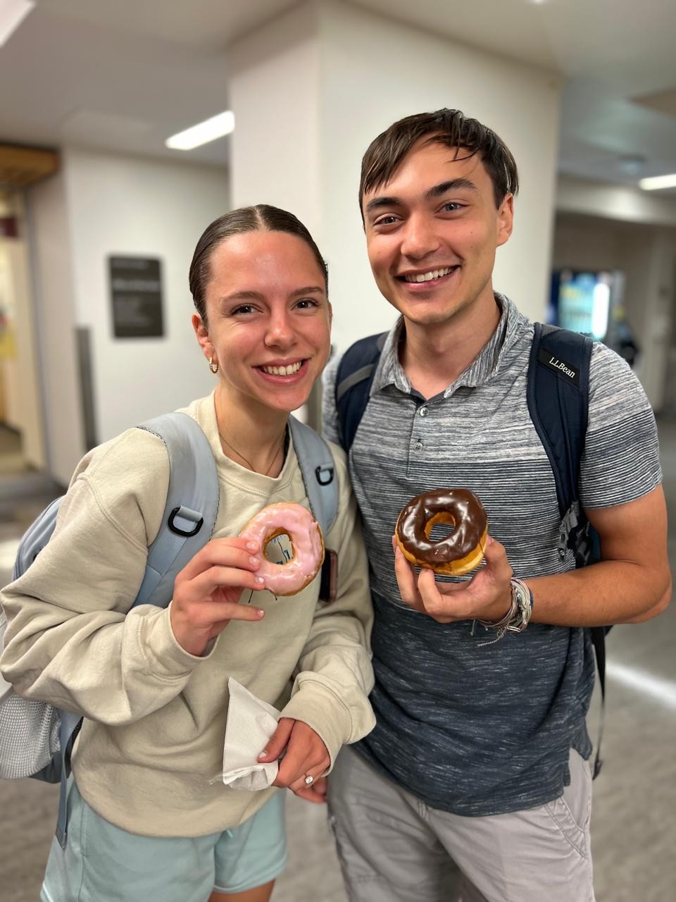 Two students posing with donuts in their hands