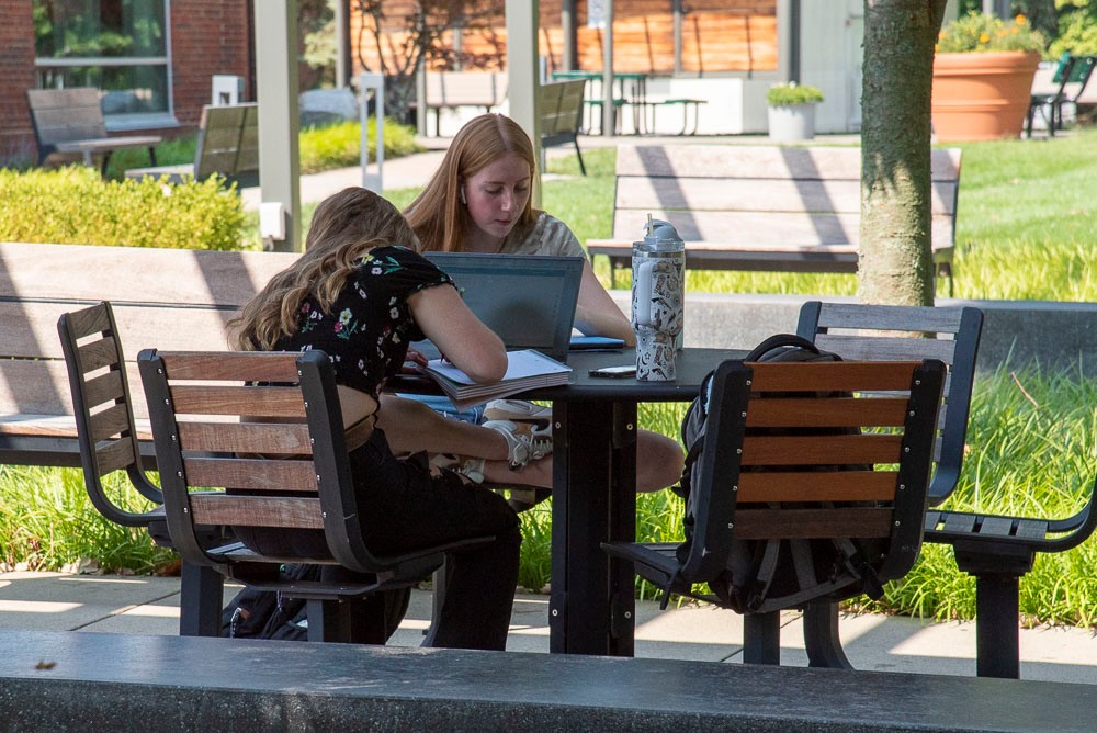 Students sitting outside at a picnic table on the UC Blue Ash campus