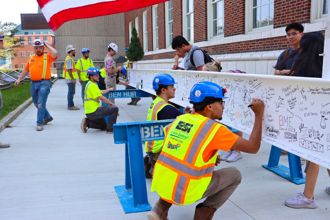 Construction crew adding signatures to the beam.