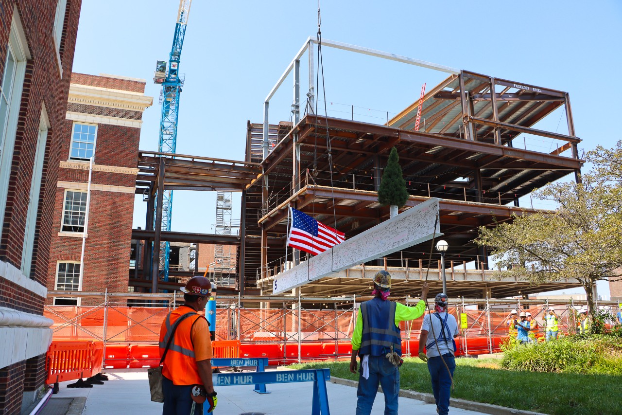 The final beam being hoisted into place, with the framework of the new addition in the background. 