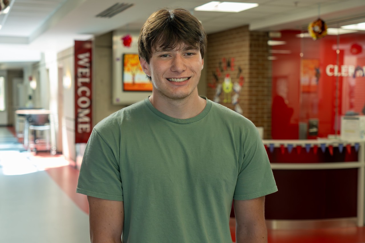 UC Clermont Summer Scholar and student Jeremiah Damen in front of the Welcome Desk