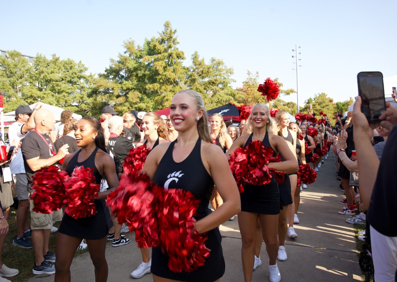 two formations of cheerleaders line up with pompoms to march