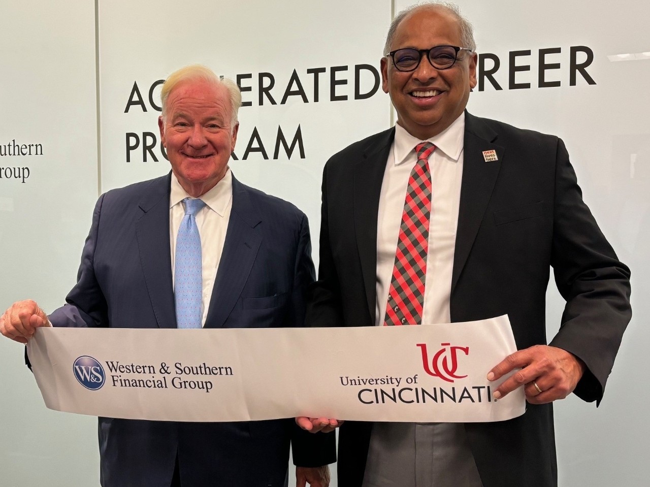 John Barrett, Western & Southern Chairman, President and CEO and University of Cincinnati President Neville G. Pinto hold up a ribbon.