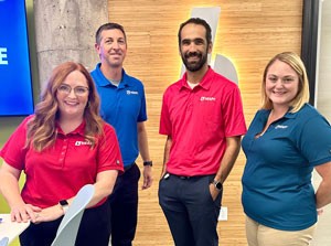 Two men and two women in Heapy polo shirts stand together in an office