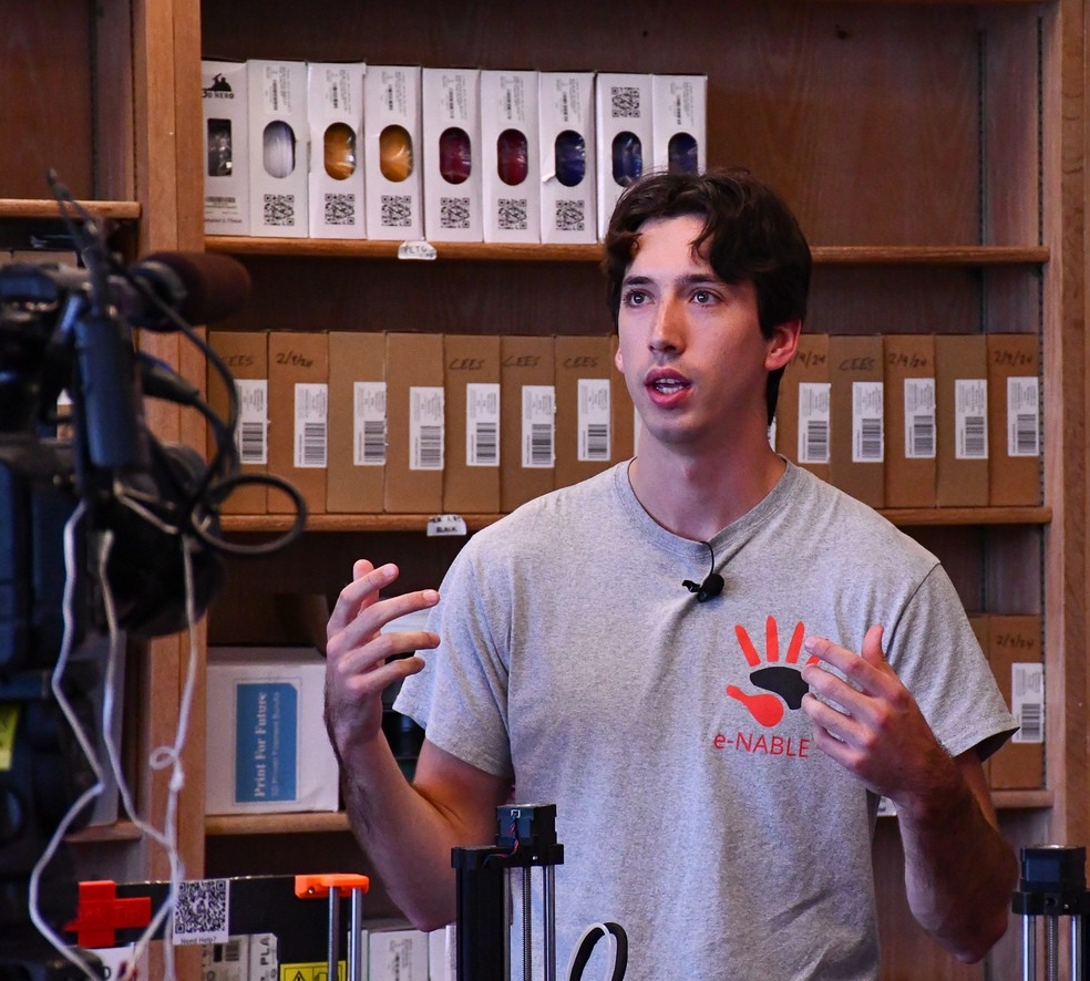 Scott Bingham gestures while talking in front of a news camera.
