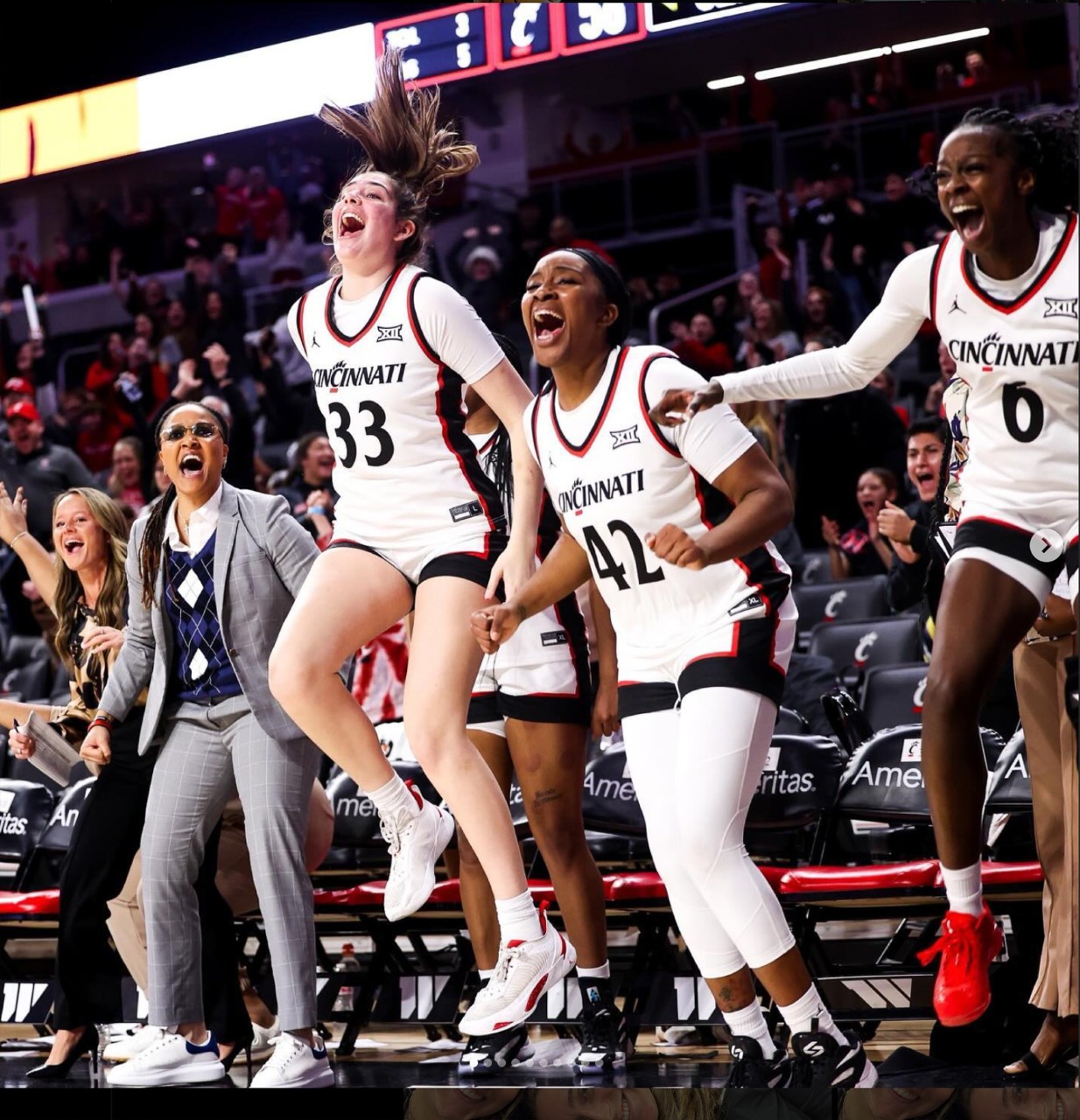 Basketball players jump in the air and shout at their teammates from the bench after a big play.