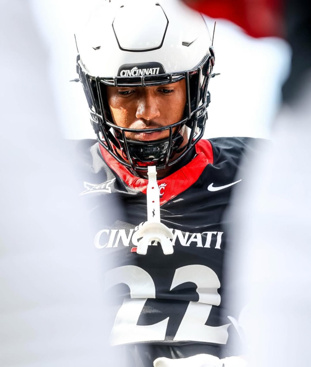 A UC football player is framed by the white uniforms of his teammates.