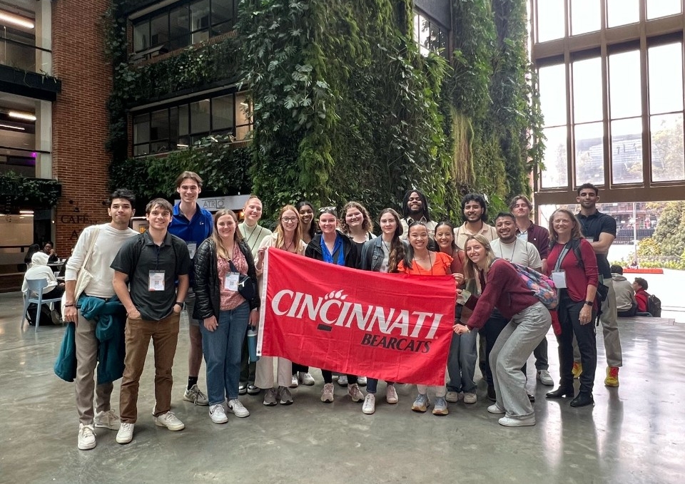 A group of people pose in front of a UC flag in Bogota.