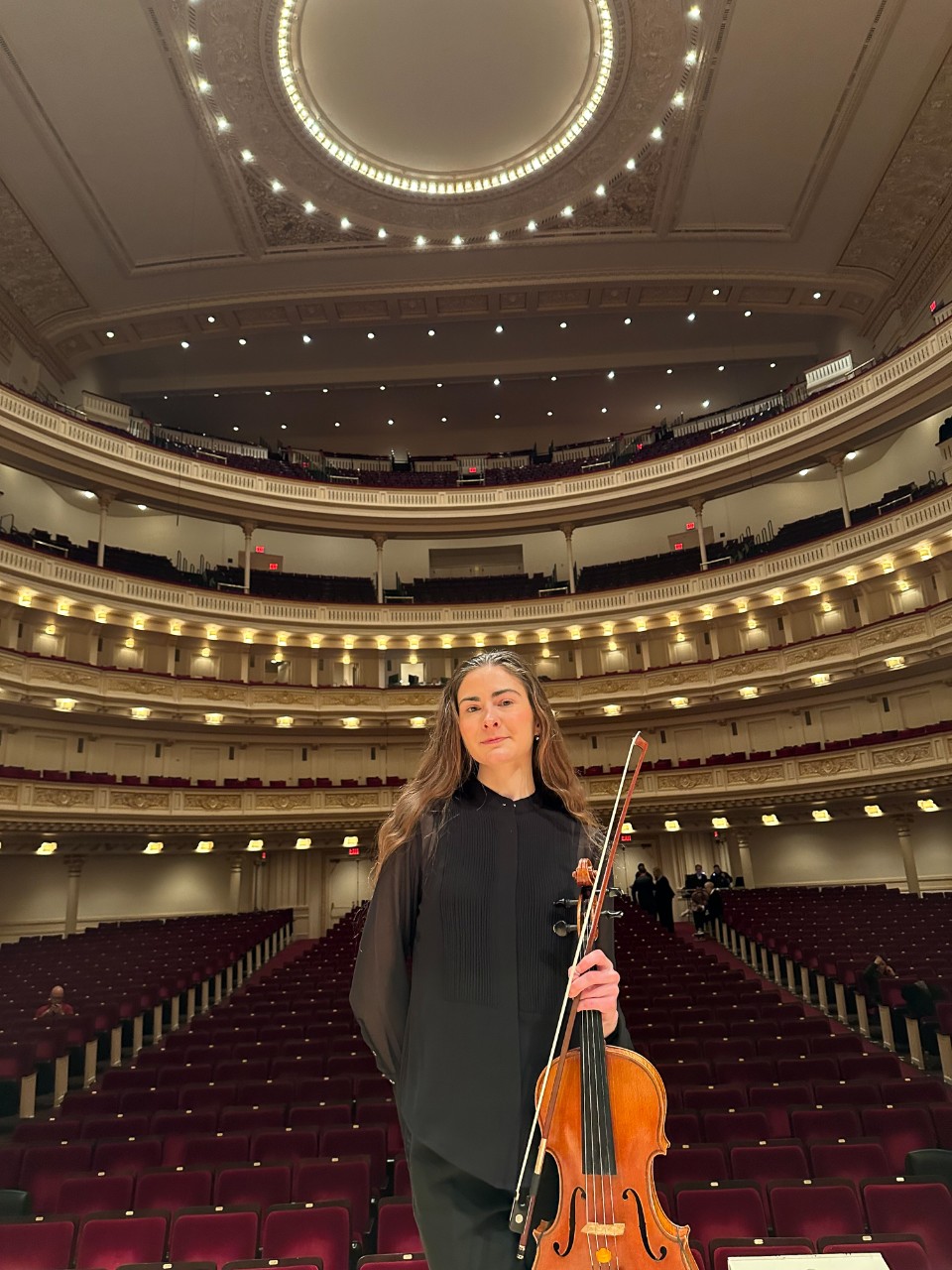 Murphy Combs poses for a photo with her viola on stage at Carnegie Hall.