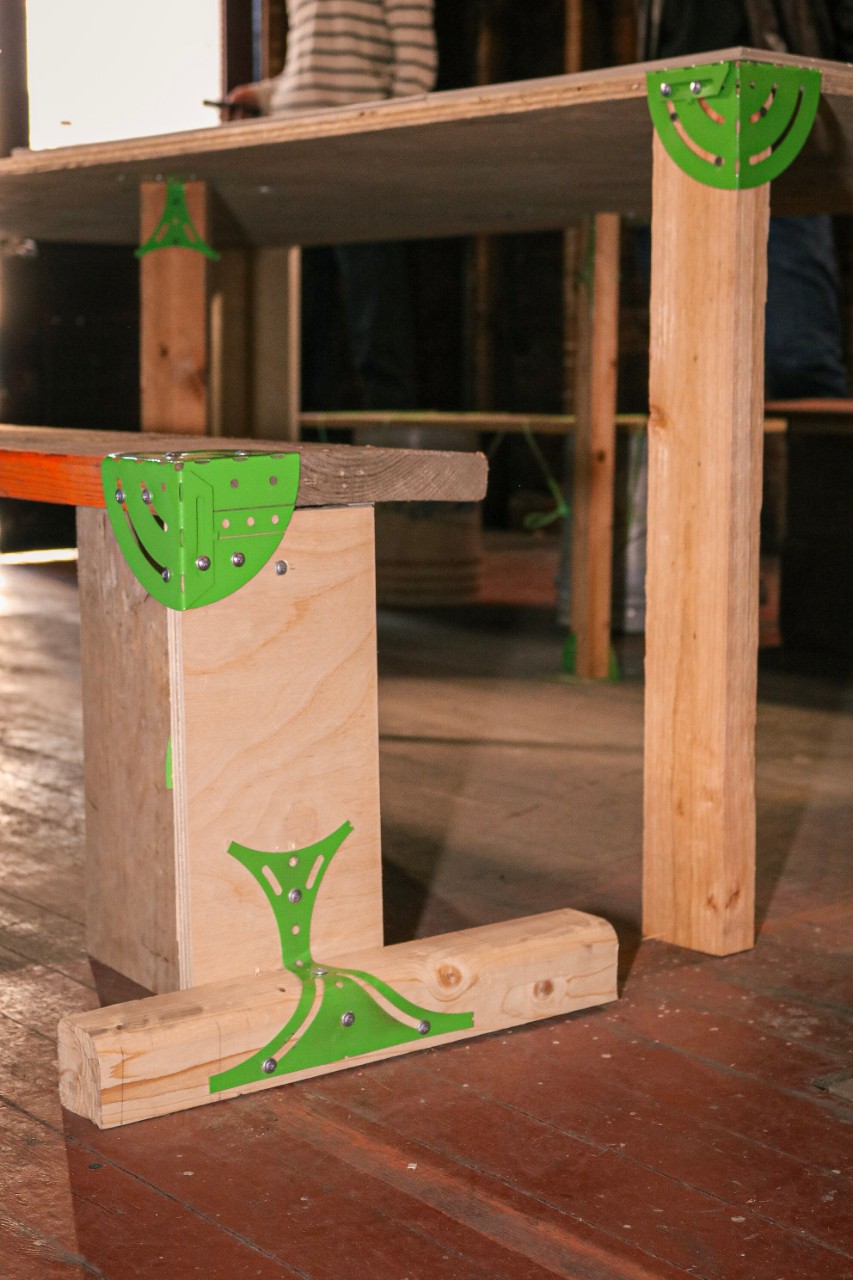 green brackets holding a chair made out of wood planks together