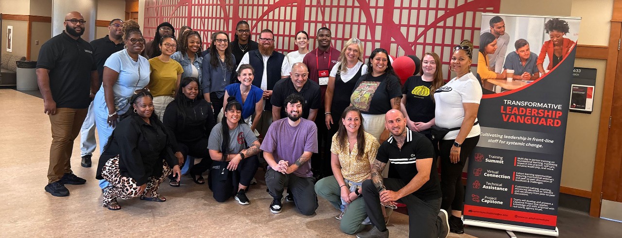 group of people pose by a sign that signs Transformational Leadership Vanguard