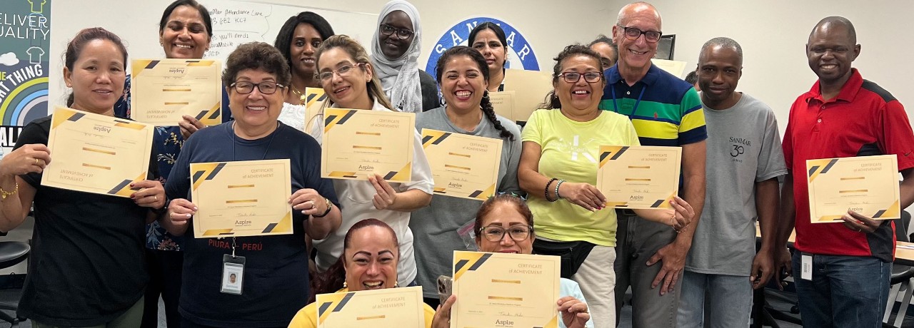 Instructor Mike Jones with participants in UC Aspire ESOL training at SanMar display certificates of completion on their final day.