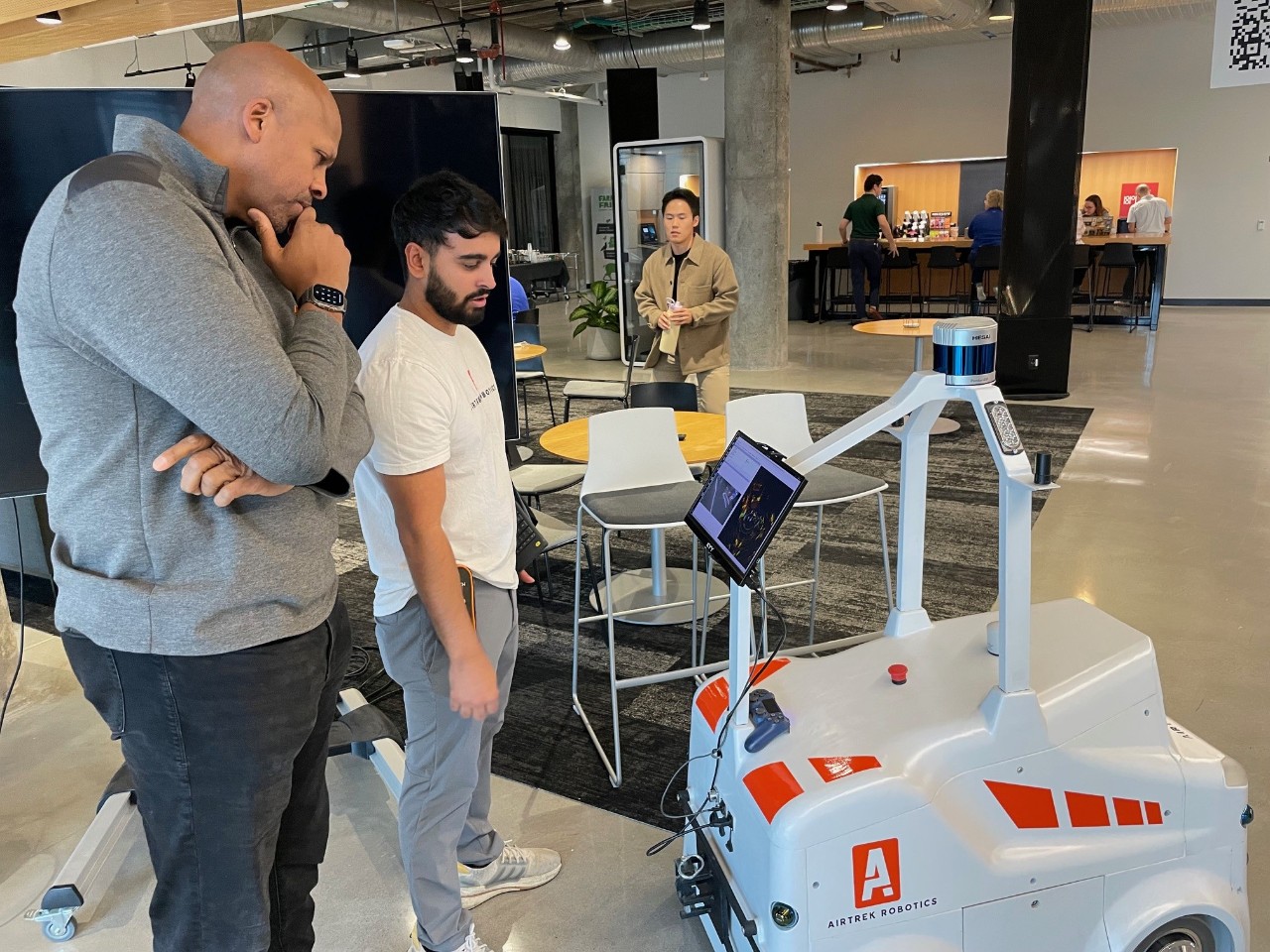 Two men look at the Airtrek robot.