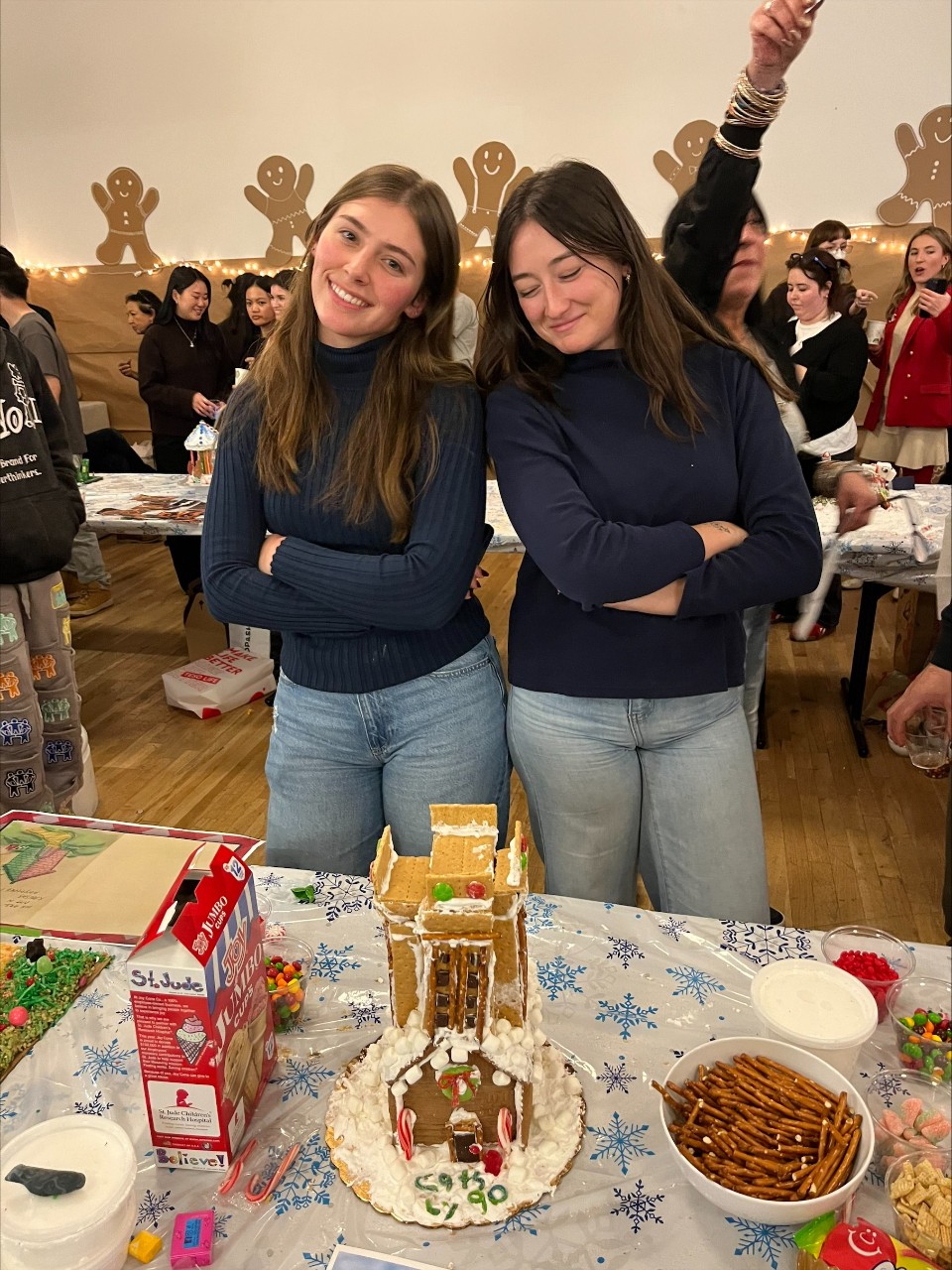 Two students shown standing in front of a gingerbread replica of Crosley Tower