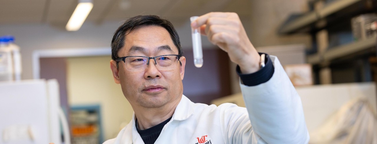 Zhang looks at a test tube he is holding in his hand in the laboratory