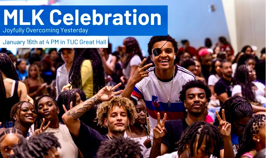 Several African Americans stand together under banner stating, "MLK celebration, joyfully overcoming yesterday."