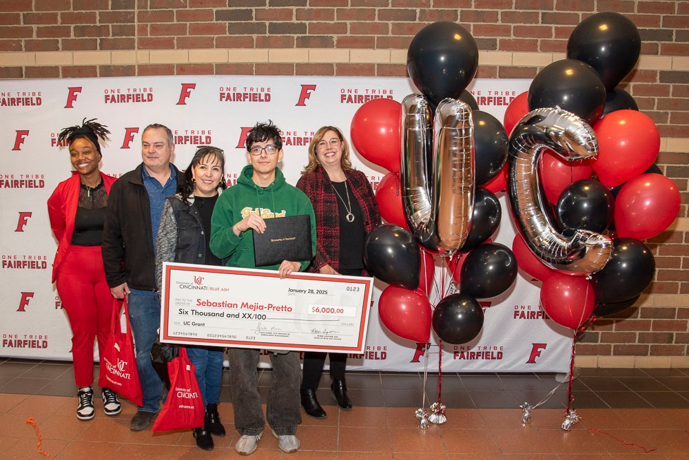 group of people holding a big check with Dean Lightner and UC balloons