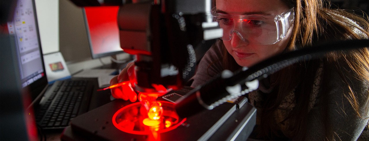 Fiona Wasson examines crystals under a red light in a chemistry lab.